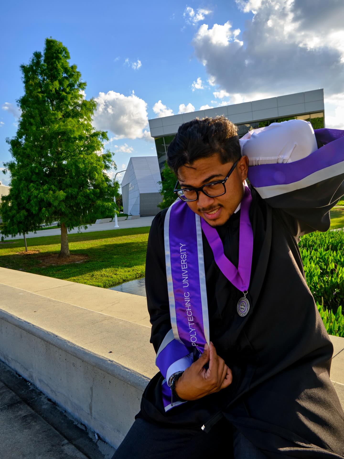 Jake in cap and gown at Florida Polytechnic University graduation, wearing a stole and medal